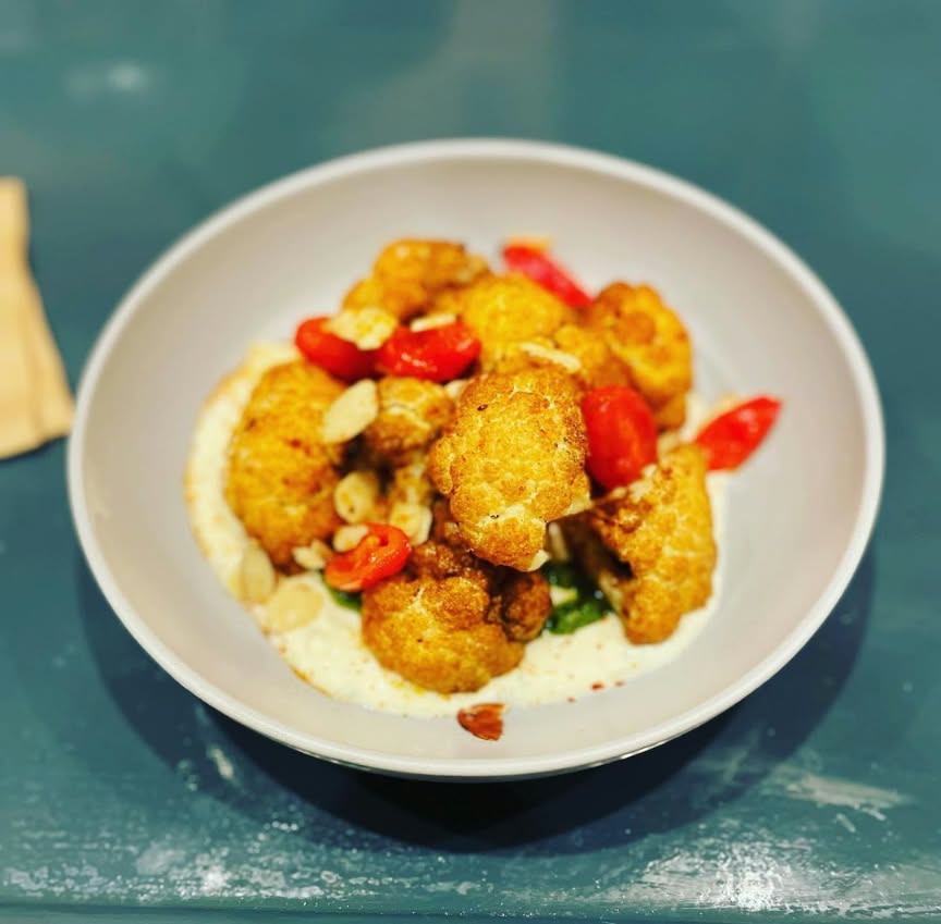 Crispy roasted cauliflower with almonds and red peppers over a creamy base