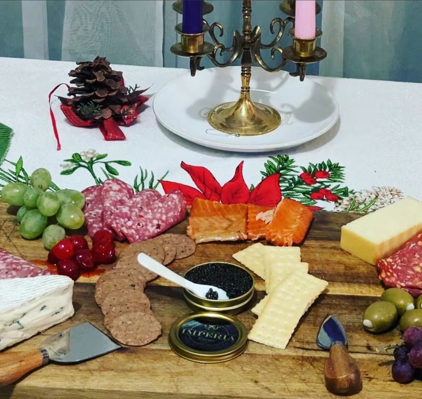 A grazing board with cured meats, salmon, cheeses, crackers, olives, grapes and caviar